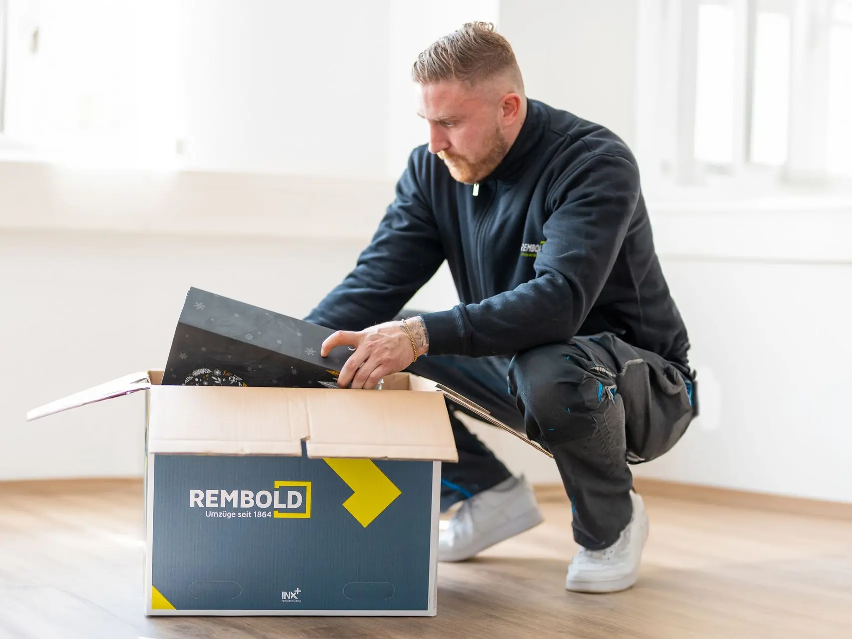 A moving company employee is packing a moving box.