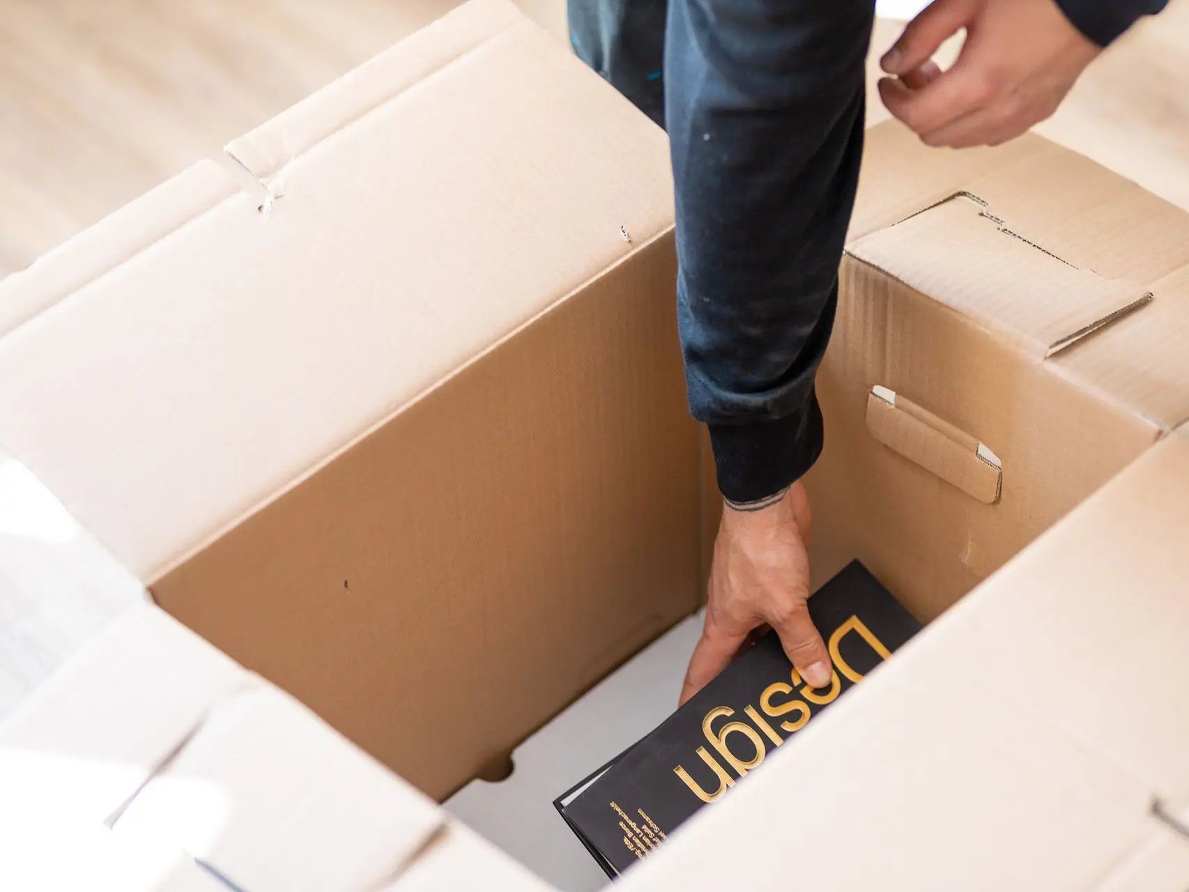 A mover is placing a book into a moving box