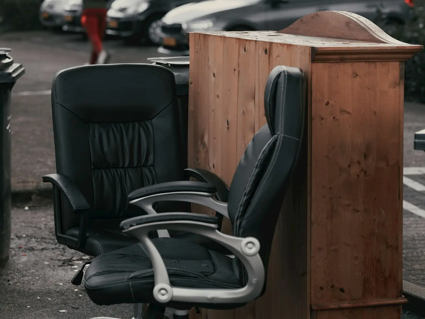 Two old office chairs and an old cabinet are sitting on the side of the street 