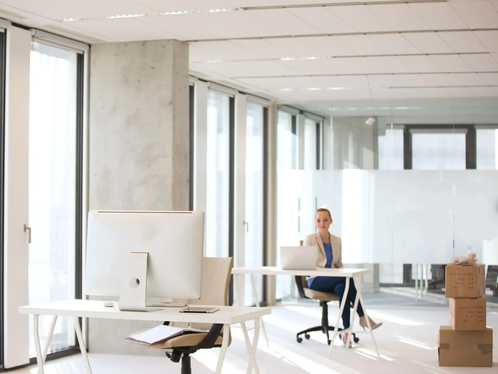 An employee sitting at her desk with moving boxes around for the office move