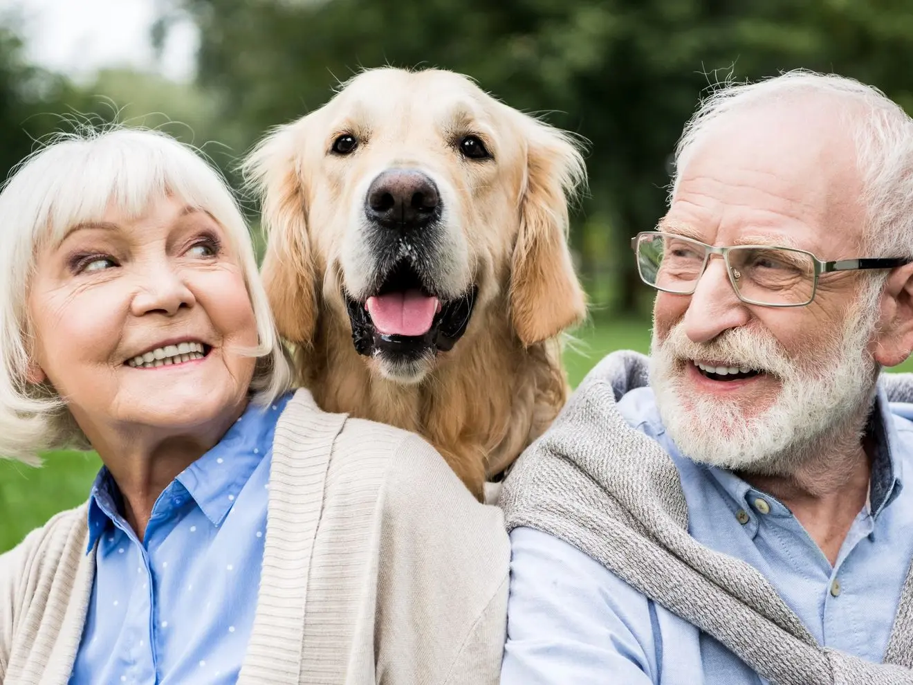 A senior couple smiling at each other while a dog sits between them