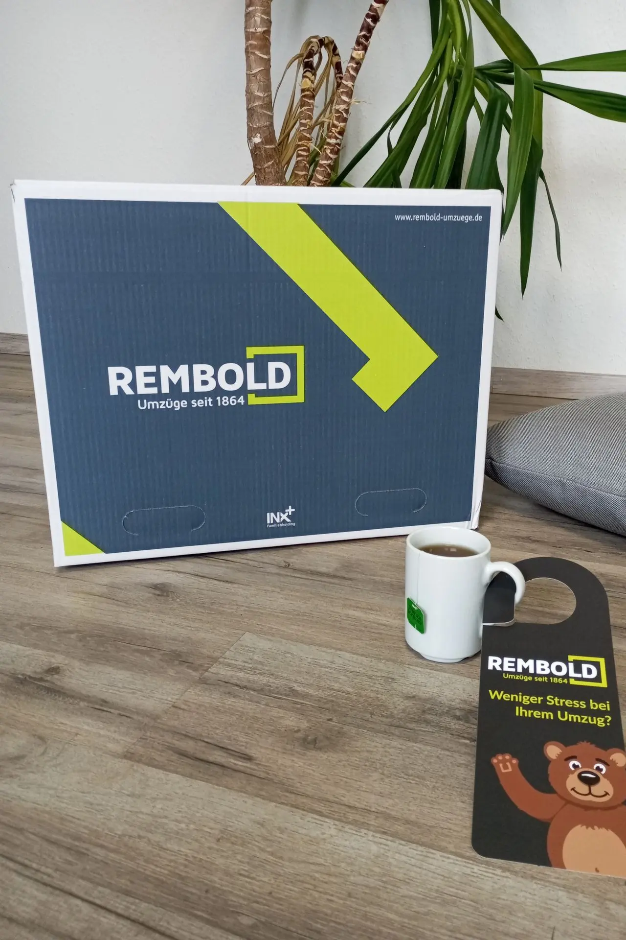 REMBOLD - Have a RELAXED move! A REMBOLD moving box and door hanger reading "REMBOLD -Less stress with your move."